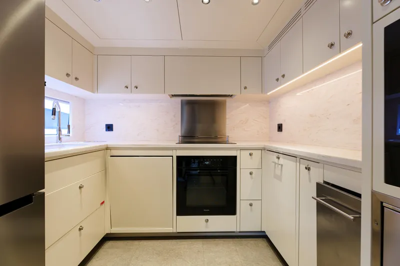 Heliophilia Yacht Photos Pics Modern kitchen interior on a 2024 Sirena 88 yacht, featuring sleek cabinetry and stainless steel appliances.
