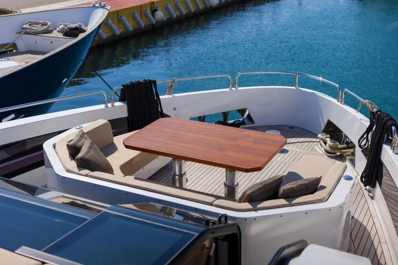Heliophilia Yacht Photos Pics Luxurious 2024 Sirena 88 yacht deck with elegant seating and wooden table by the water.