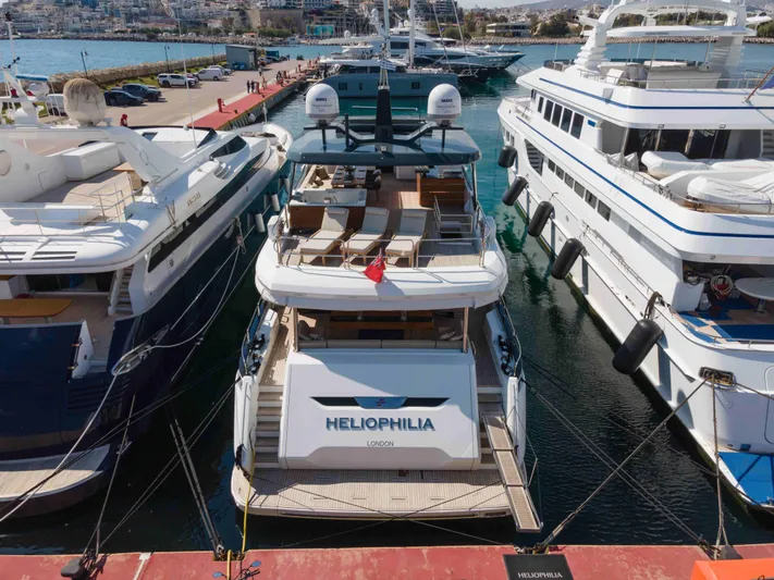 Heliophilia Yacht Photos Pics Luxury yacht Sirena 88, 2024 model, docked at a marina between other yachts.