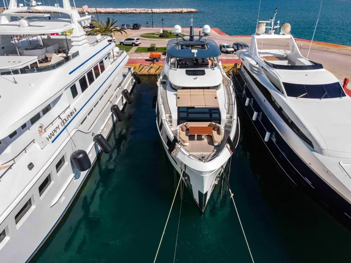 Heliophilia Yacht Photos Pics 2024 Sirena 88 yacht docked between two other luxury yachts in a marina.