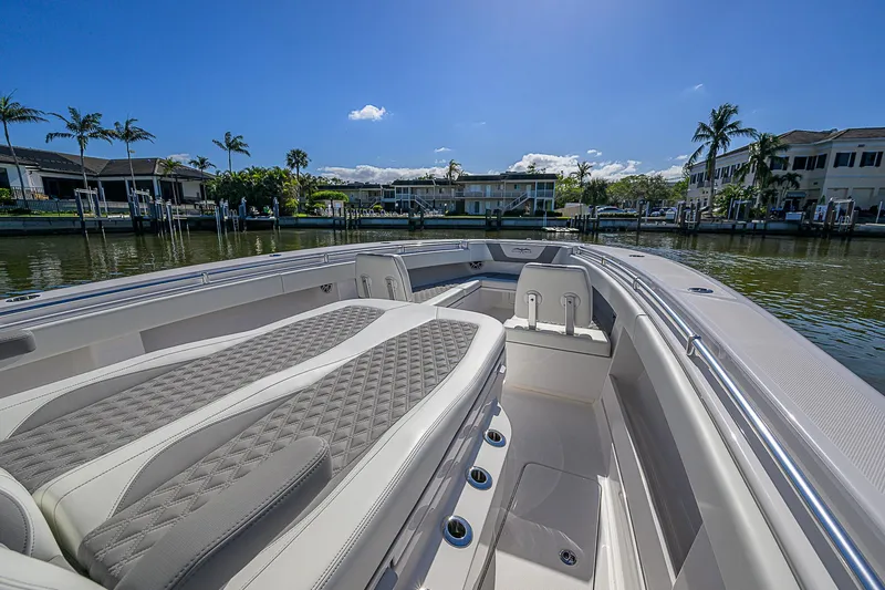  Yacht Photos Pics 2024 Invincible 39 Open Fisherman boat with luxurious seating, docked by waterfront homes.