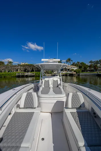  Yacht Photos Pics 2024 Invincible 39 Open Fisherman boat on a sunny day, docked by lush greenery.