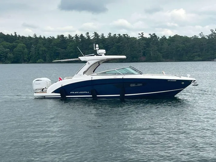  Yacht Photos Pics 2025 Regal 33 OBX boat on a calm lake with forested shoreline.