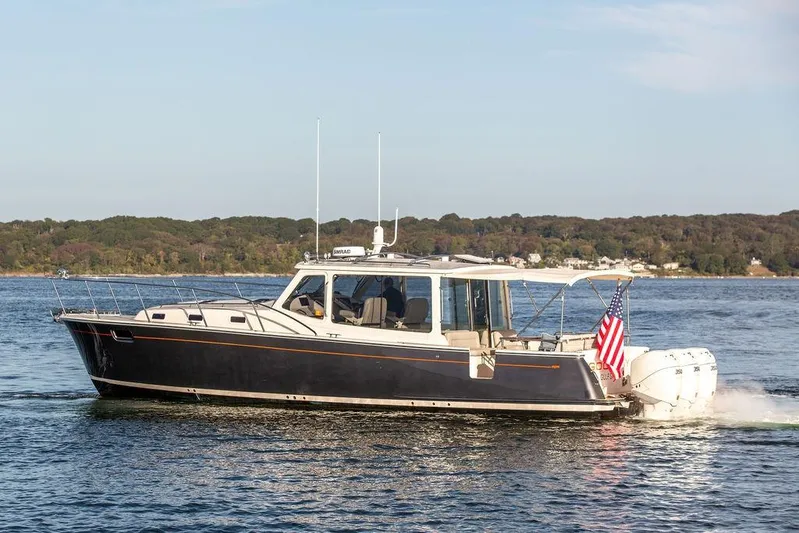 Goombay Yacht Photos Pics 2018 MJM 43z boat cruising on a serene lake with forested shoreline.