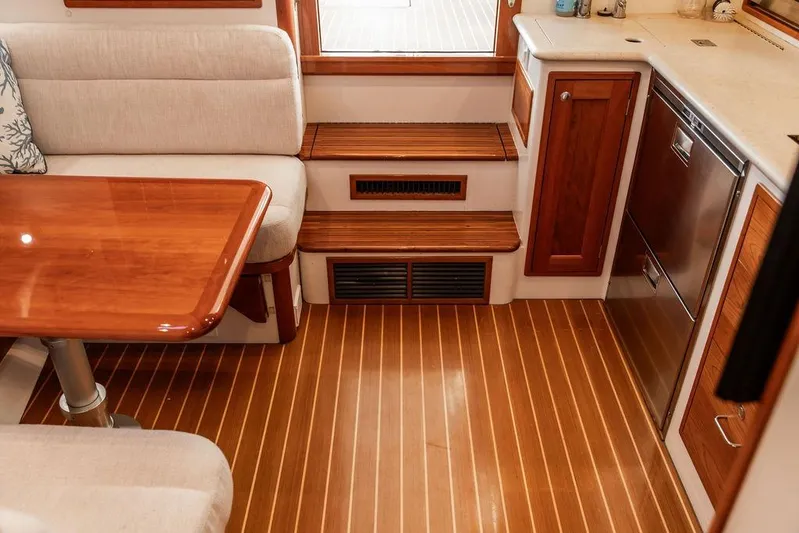 Goombay Yacht Photos Pics Interior of a 2018 MJM 43z yacht featuring a wooden table, seating, and kitchenette.