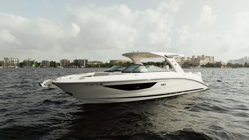  Yacht Photos Pics 2023 Sea Ray 350 Sundancer yacht on water, cityscape background, cloudy sky.