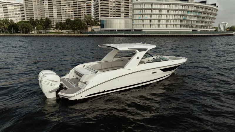  Yacht Photos Pics 2023 Sea Ray 350 Sundancer boat on water, with modern buildings in the background.