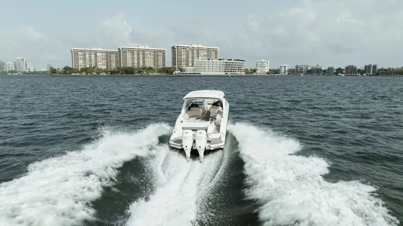  Yacht Photos Pics 2023 Sea Ray 350 Sundancer cruising on open water near city skyline.