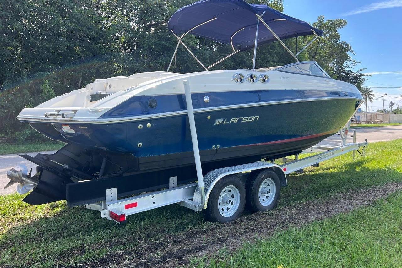 2013 Larson LXi 292 IO boat on trailer, parked on grass, with blue canopy.