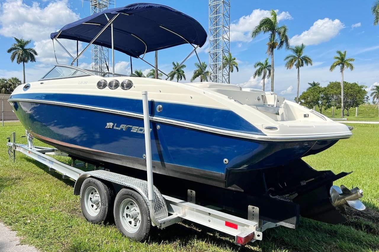 2013 Larson LXi 292 IO boat on trailer, blue and white, parked on grass.