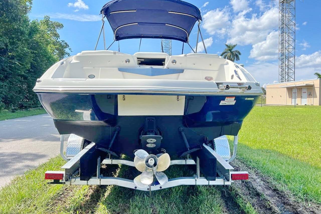 2013 Larson LXi 292 IO boat on trailer, parked on grass under blue sky.