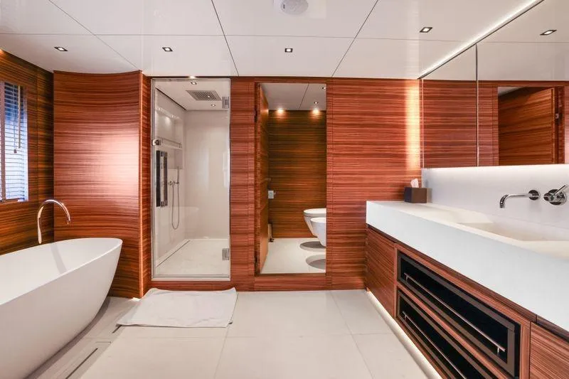Magna Grecia Yacht Photos Pics Luxurious yacht bathroom with modern design, featuring wood paneling, bathtub, and glass shower.