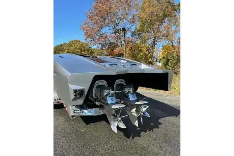  Yacht Photos Pics 2020 Outerlimits SL-50 boat with dual propellers, parked on a trailer, surrounded by autumn trees.