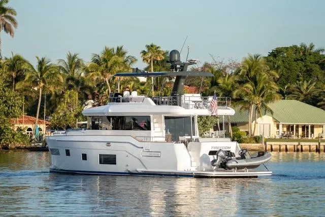 Freedom Yacht Photos Pics 2022 Sirena 58 Flybridge yacht cruising near tropical shoreline with palm trees.