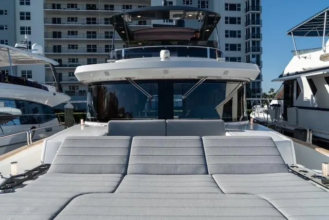 Freedom Yacht Photos Pics Sirena 58 Flybridge 2022 yacht with spacious sunbathing area, docked near modern buildings.