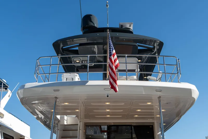 Freedom Yacht Photos Pics Sirena 58 Flybridge 2022 yacht with American flag, viewed from the stern under clear blue sky.
