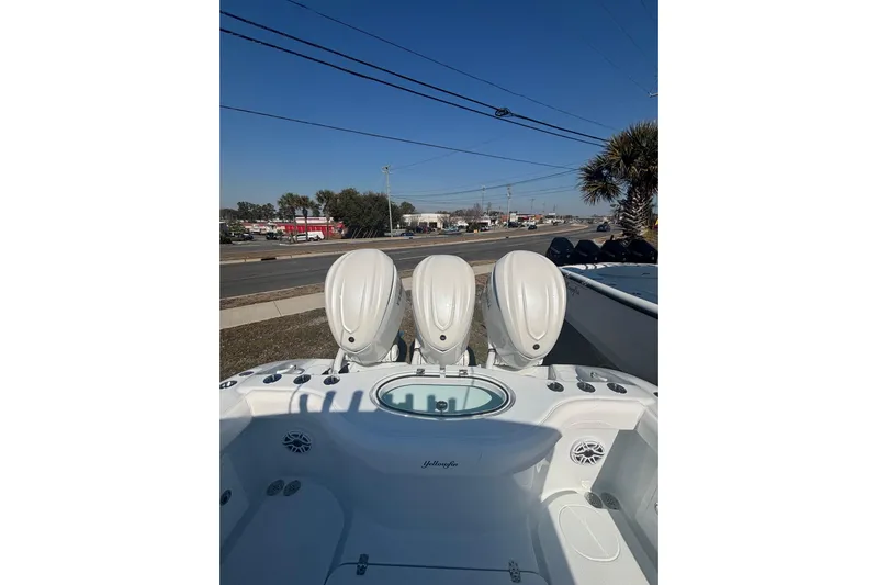  Yacht Photos Pics 2026 Yellowfin 36 Offshore boat with triple outboard engines, parked near a road.