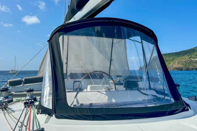 Sailifi Yacht Photos Pics 2007 Lagoon 440 catamaran cockpit with clear enclosure, ocean and island backdrop.