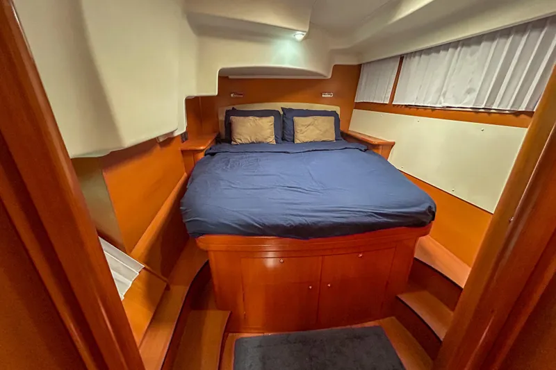 Sailifi Yacht Photos Pics Luxurious cabin interior of 2007 Lagoon 440 catamaran with cozy bed and wooden finish.