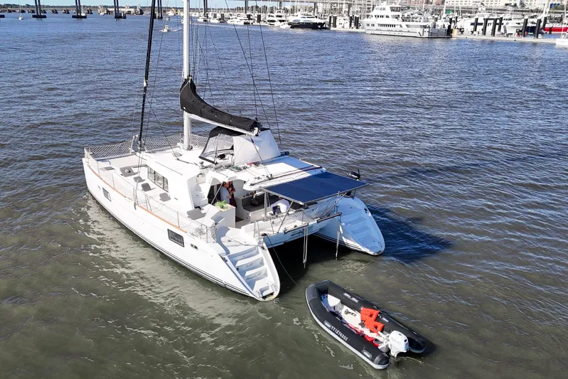 Sailifi Yacht Photos Pics 2007 Lagoon 440 catamaran anchored with a small dinghy nearby in a marina.