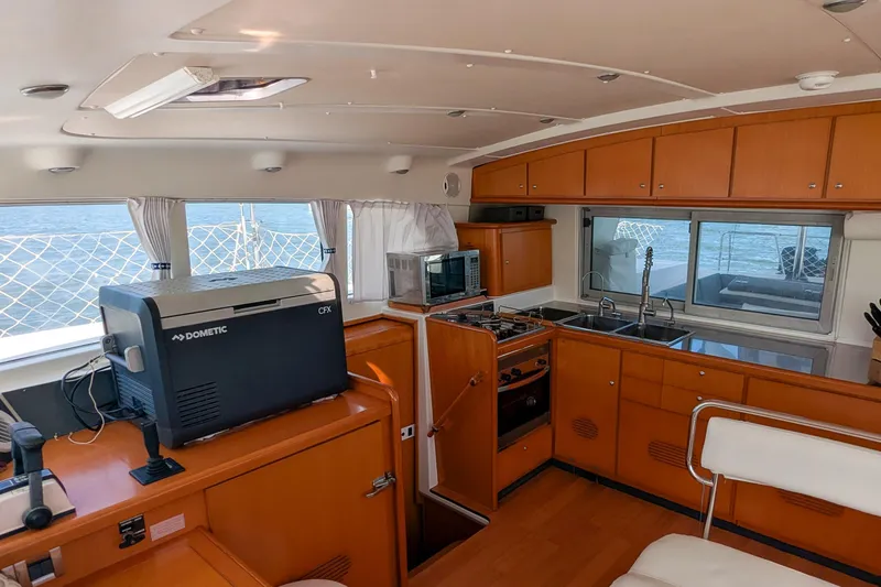 Sailifi Yacht Photos Pics Interior of 2007 Lagoon 440 catamaran with kitchen and appliances, featuring wood cabinetry.