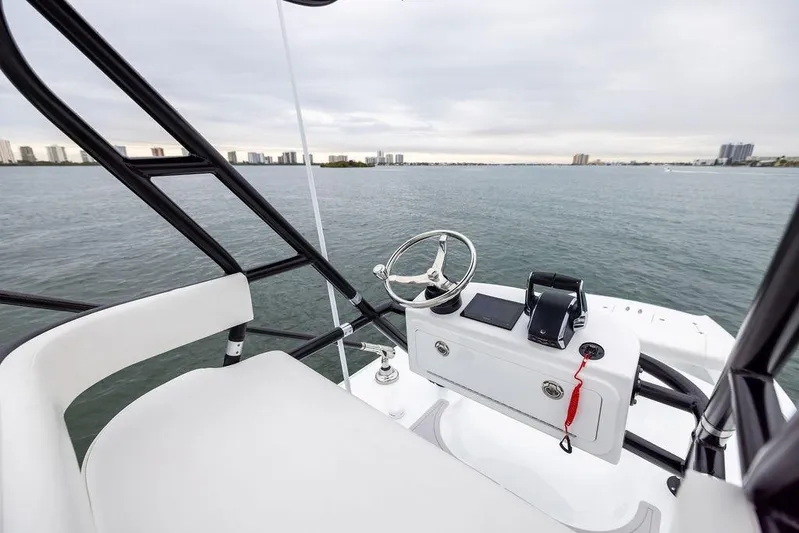 Never Enough Yacht Photos Pics 2025 Freeman 38 boat helm with steering wheel, overlooking calm waters and city skyline.