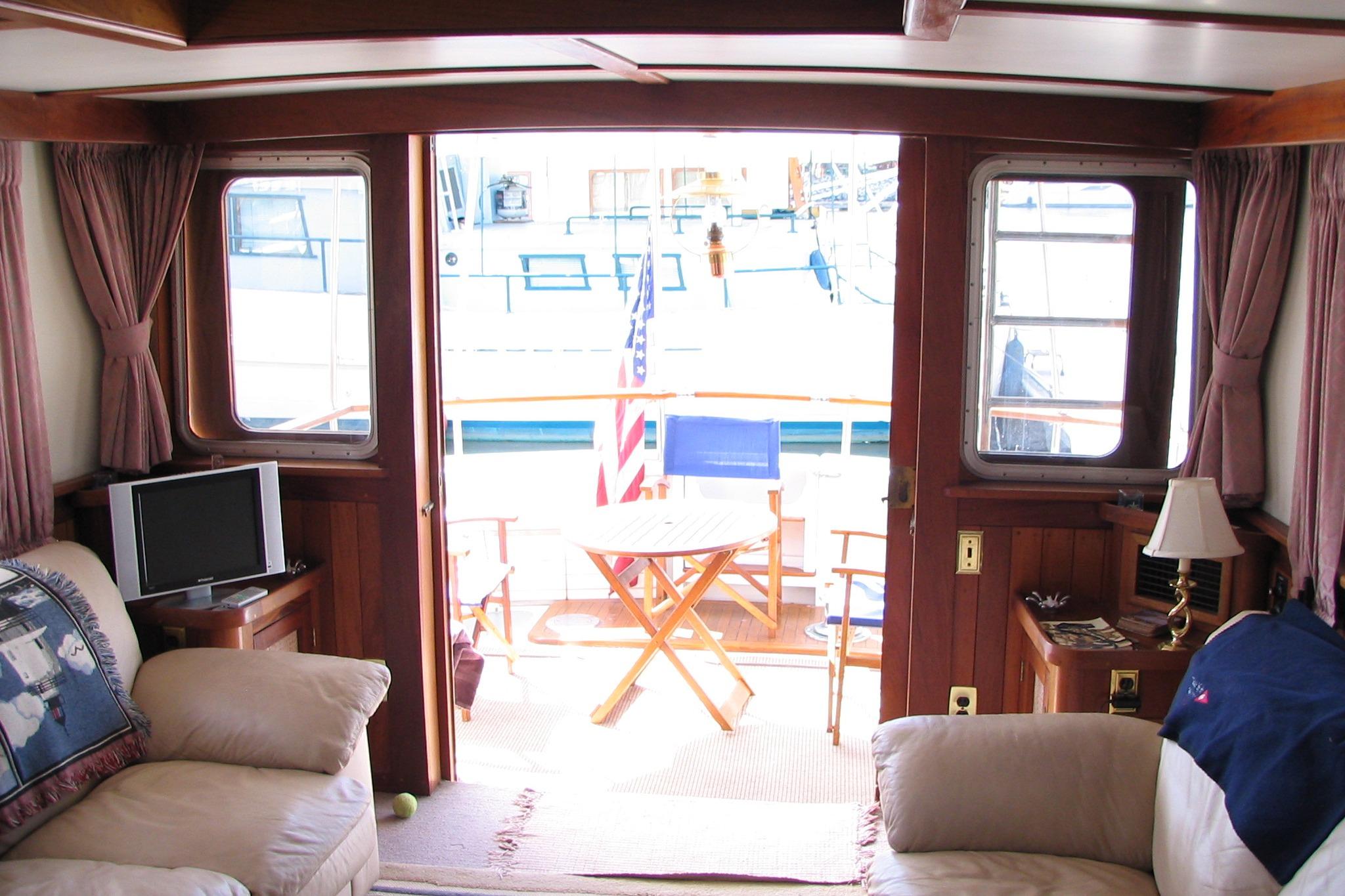 Interior of a 1989 Custom 52 Pilothouse yacht with cozy seating and outdoor deck view.