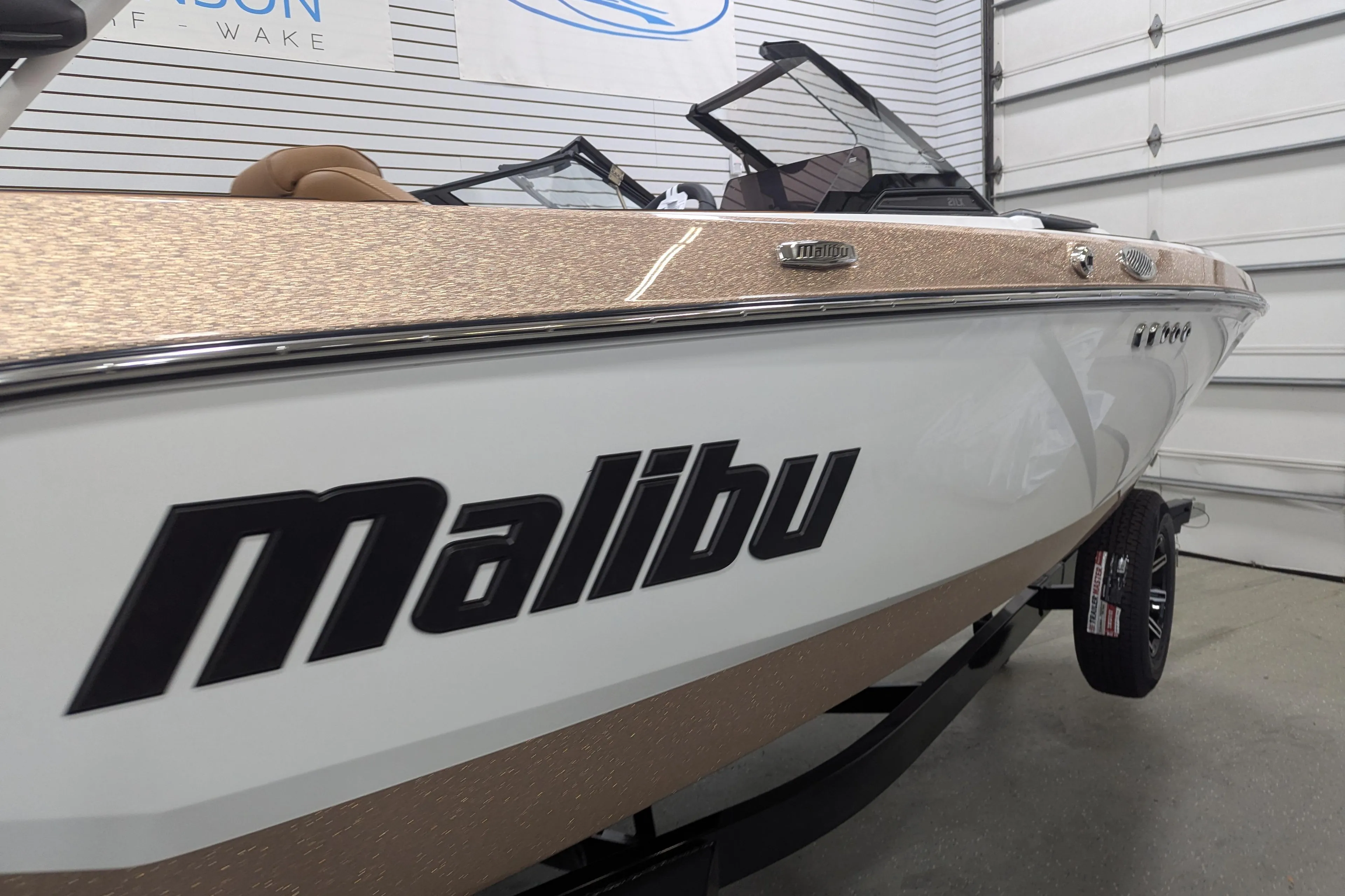 2026 Malibu Wakesetter 21 LX boat in showroom, featuring sleek design and branding.