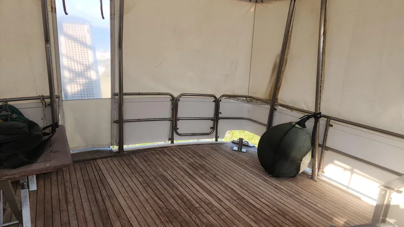 Orly Yacht Photos Pics Wooden deck with metal railings inside a tented structure, featuring a bag and city view.