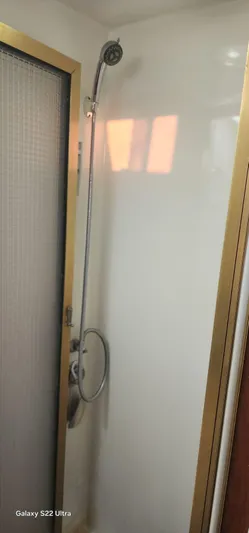 Orly Yacht Photos Pics Shower area with handheld showerhead, gold trim, and frosted glass door in a 1990 President 465.