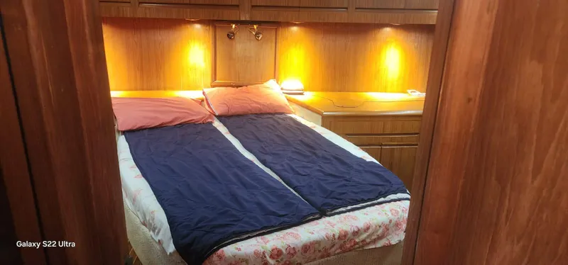 Orly Yacht Photos Pics Cozy bedroom with twin beds, warm lighting, and wooden cabinetry in a 1990 President 465 yacht.