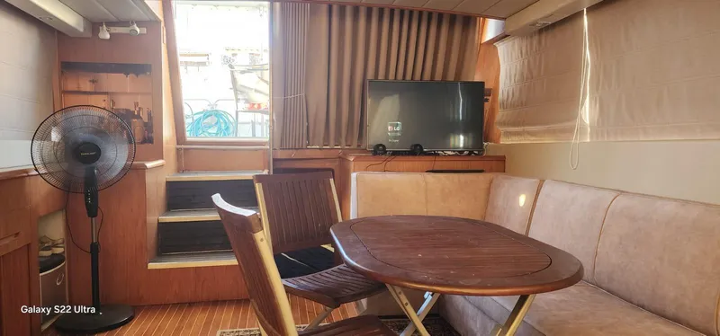 Orly Yacht Photos Pics Cozy yacht interior with wooden table, chairs, TV, and fan, President 465 model, 1990.