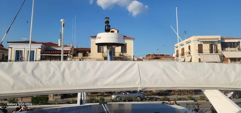 Orly Yacht Photos Pics Boat deck view with radar, solar panels, and coastal town backdrop under clear blue sky.