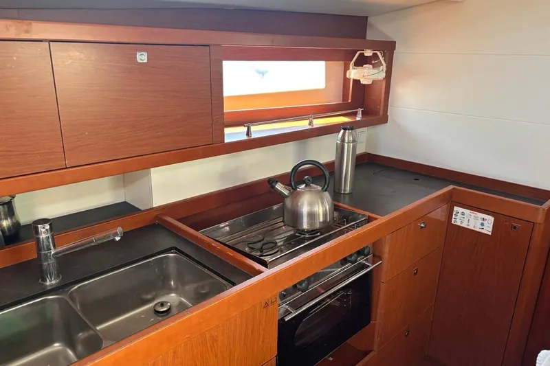 Yacht Photos Pics Modern kitchen in a 2019 Beneteau Oceanis 45 yacht with wooden cabinetry and stainless steel appliances.