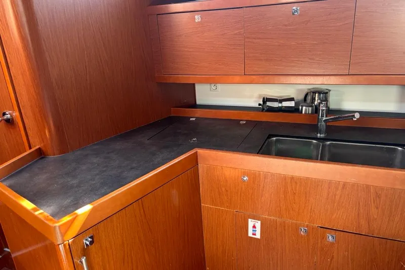  Yacht Photos Pics Galley kitchen in 2019 Beneteau Oceanis 45 yacht with wood cabinetry and modern sink.