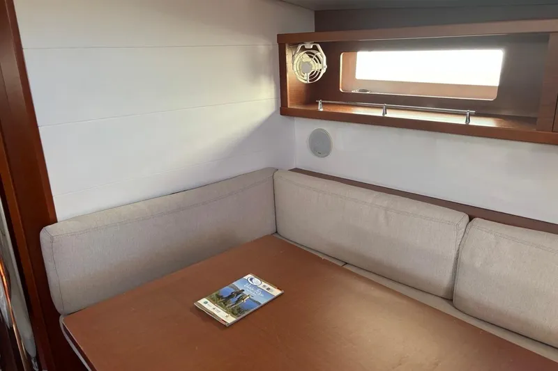 Yacht Photos Pics Cozy interior of 2019 Beneteau Oceanis 45 yacht with cushioned seating and table.