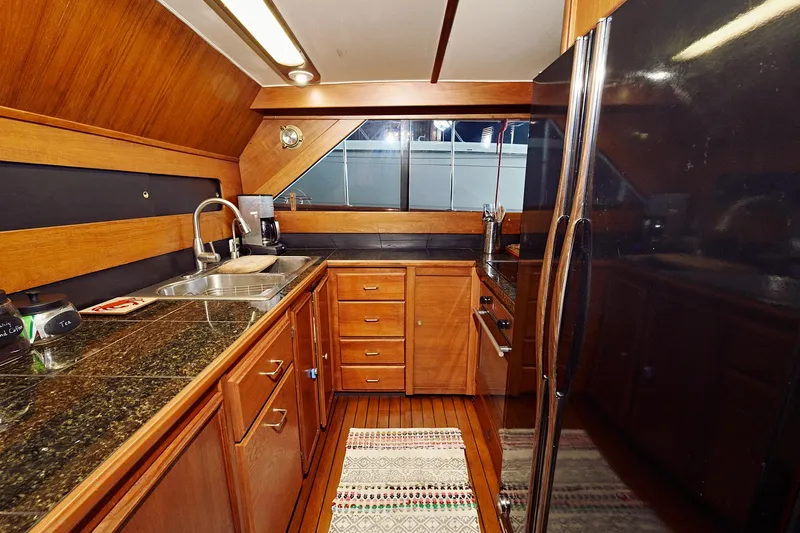 Camelot Yacht Photos Pics 1976 Pacemaker 65 yacht kitchen with wooden cabinets and granite countertops.