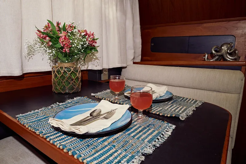 Camelot Yacht Photos Pics Elegant dining setup on a 1976 Pacemaker 65 yacht with flowers and drinks.