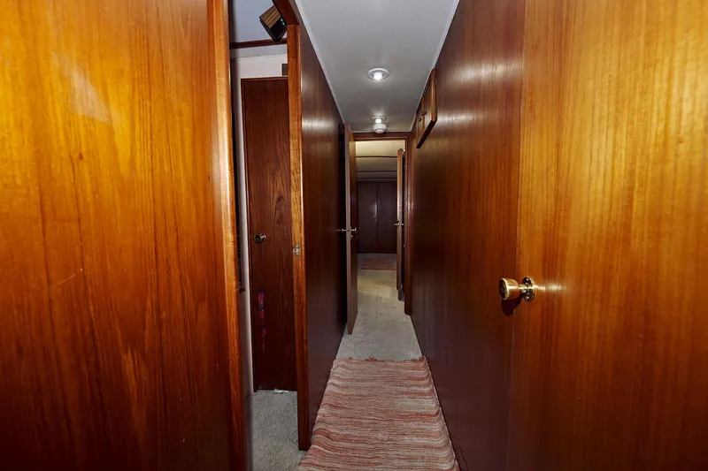 Camelot Yacht Photos Pics 1976 Pacemaker 65 yacht interior hallway with wooden paneling and carpet.