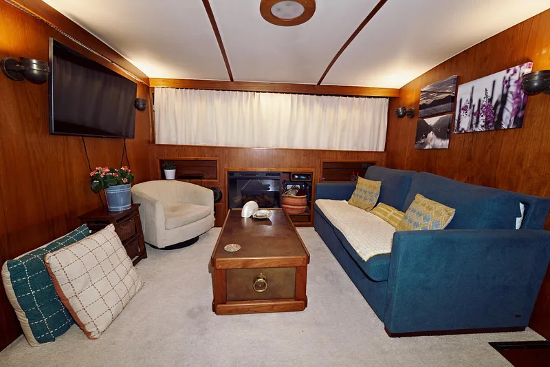 Camelot Yacht Photos Pics Cozy 1976 Pacemaker 65 yacht interior with blue sofa, armchair, and wooden decor.
