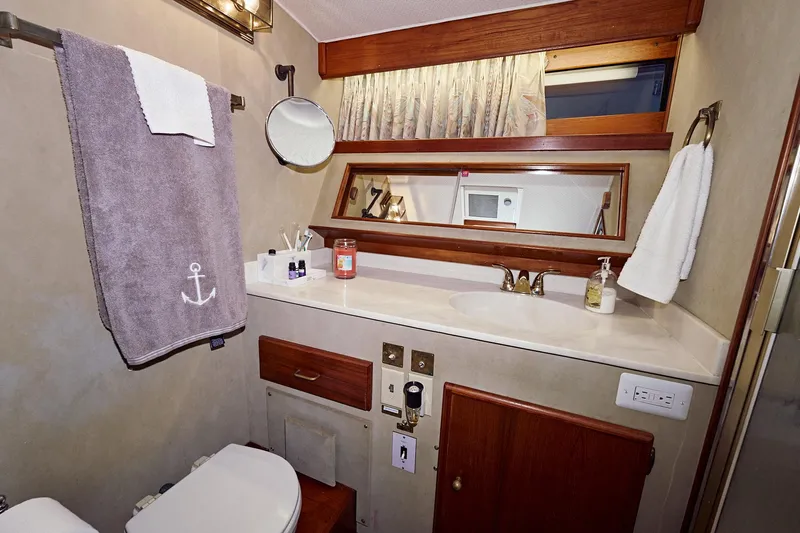Camelot Yacht Photos Pics 1976 Pacemaker 65 yacht bathroom with vanity, mirror, and towel rack.