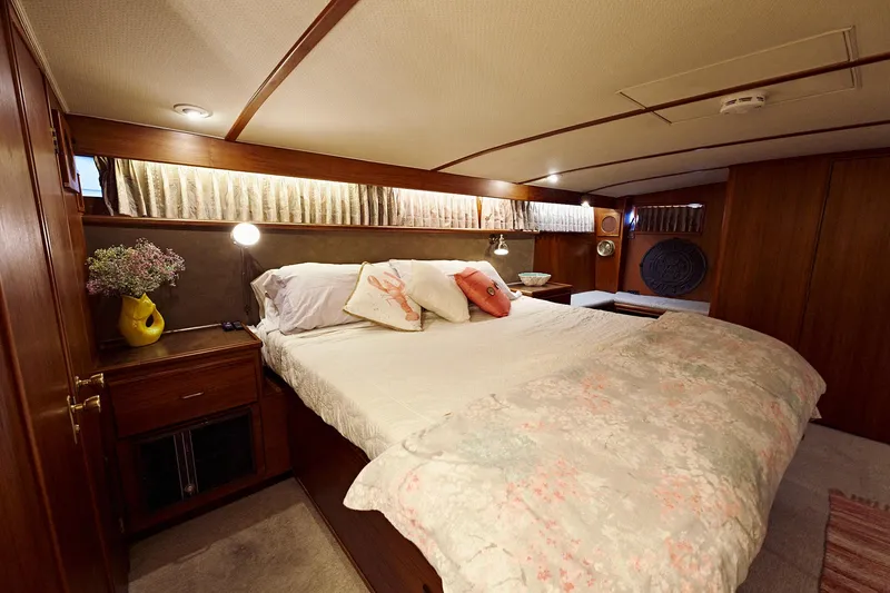 Camelot Yacht Photos Pics Luxurious bedroom in a 1976 Pacemaker 65 yacht with cozy bedding and wooden decor.