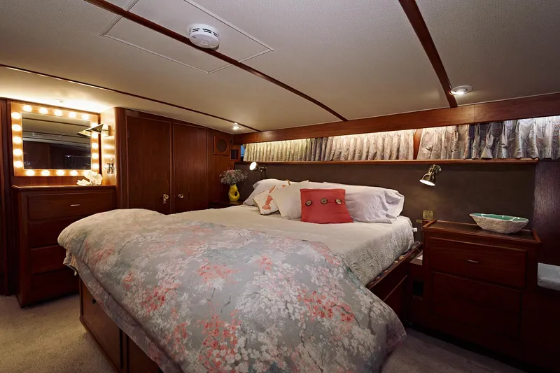 Camelot Yacht Photos Pics Luxurious bedroom interior of a 1976 Pacemaker 65 yacht with cozy bedding and wooden furnishings.