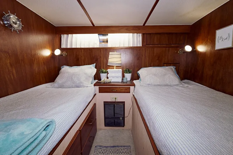 Camelot Yacht Photos Pics Twin bed cabin interior of 1976 Pacemaker 65 yacht with wooden walls and cozy decor.