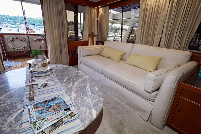 Camelot Yacht Photos Pics Interior of 1976 Pacemaker 65 yacht with sofa, table, and marina view.