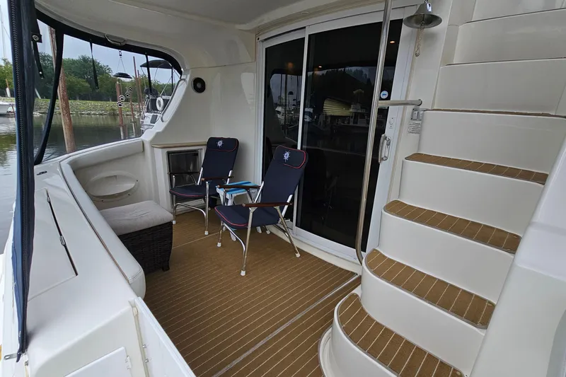  Yacht Photos Pics 2007 Silverton 38 Sport Bridge yacht deck with chairs and stairs, docked by the water.