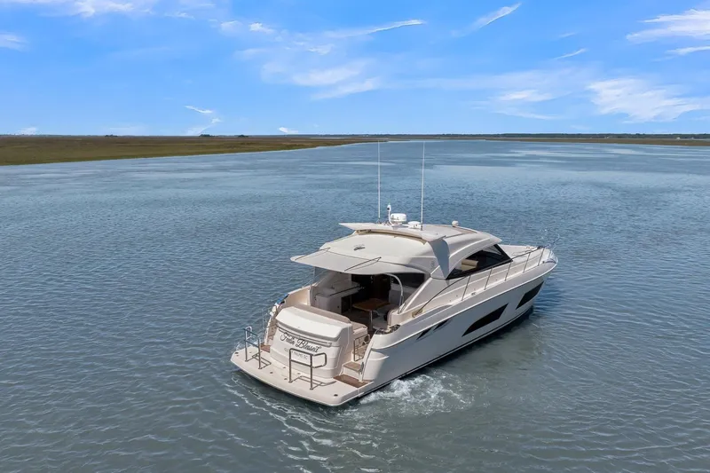  Yacht Photos Pics 2020 Riviera 4800 Sport Yacht cruising on a serene waterway under a clear blue sky.