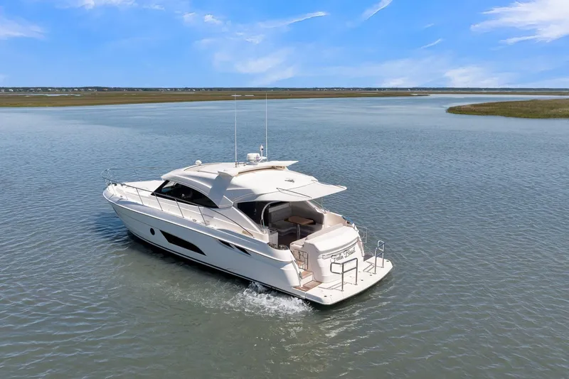  Yacht Photos Pics 2020 Riviera 4800 Sport Yacht cruising on calm waters under a clear blue sky.