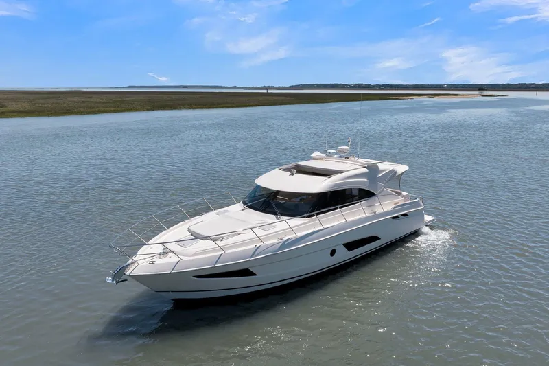  Yacht Photos Pics 2020 Riviera 4800 Sport Yacht cruising on a serene waterway under a clear blue sky.