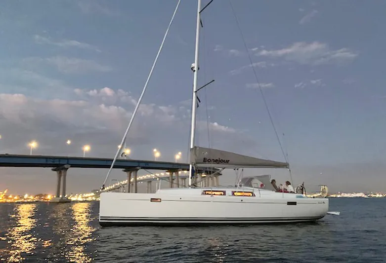 Bonejour Yacht Photos Pics Sailing yacht Hanse 385, 2012 model, on calm waters at dusk near a lit bridge.